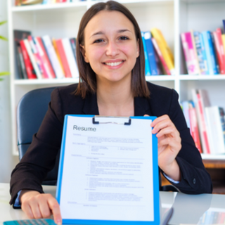 Image of a woman in front of a bookcase showing a resume on a clipboard