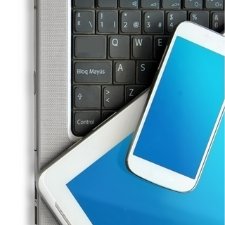 A white phone on top of a white tablet on top of a silver and black laptop.