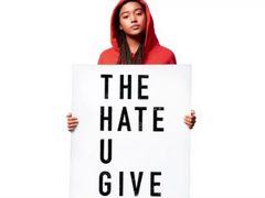 Cover of The Hate U Give Film: A teenage girl wearing a red hoodie stares directly at the camera, while holding up a large sign that reads 