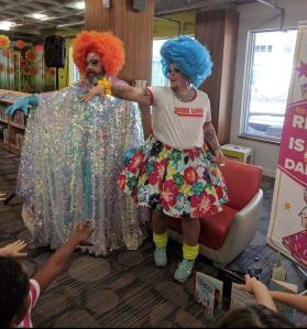 A photo from inside Kitchener Public Library showing drag queens Fay and Fluffy performing a song and interactive dance for kids in 2019.