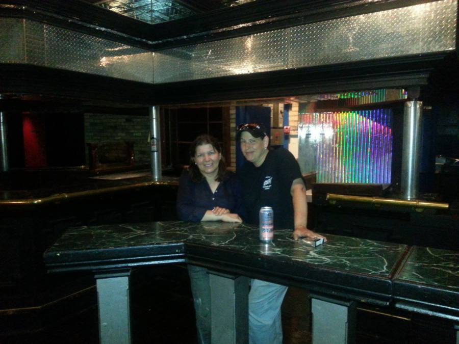 A photo inside of Club Renaissance after it has closed. Owners Fran and Cheryl pose for a last photo together at Club Renaissance in front of the bar.