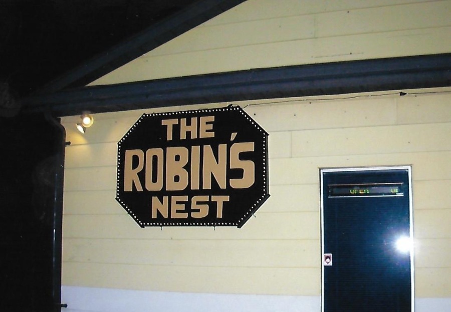 A photo of a building with a large sign reading "The Robin's Nest". Beside the sign there is a door with a sign that reads "open".