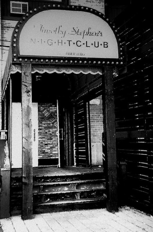 A photo from the outside of Timothy Stephen's Nightclub showing a sign with lights around it above steps entering into the club.