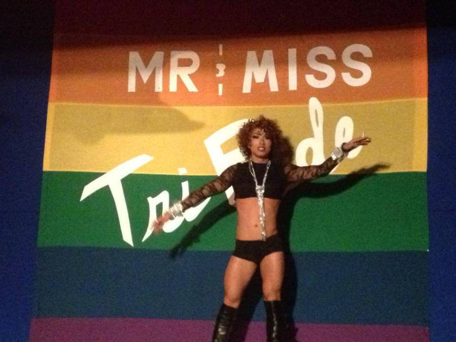 A photo of a drag queen in knee high black leather boots, hot pants, a lacy black shirt, silver jewelry and a short curly wig performs on stage at Club Renaissance during the Mr and Miss TriPride Pageant in 2013.