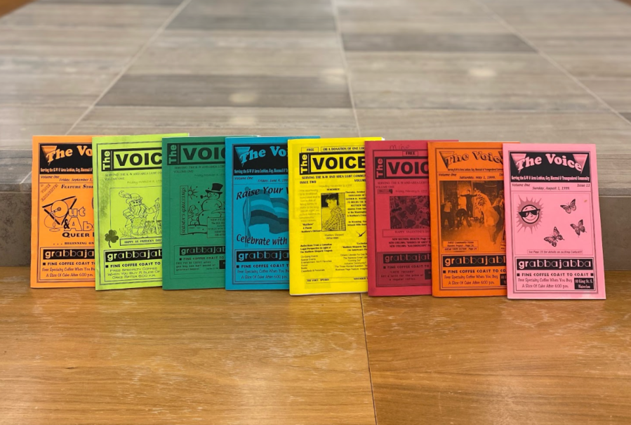 A photo of an colourful array of issues of The Voice magazines. The voice was a free, local LGBTQ+ monthly that was distributed throughout the Tri-Cities as well as Hamilton and Toronto.